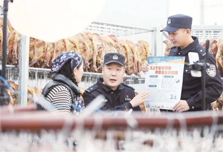 在辖区腊货食品加工企业，民警向员工宣传反诈知识。
