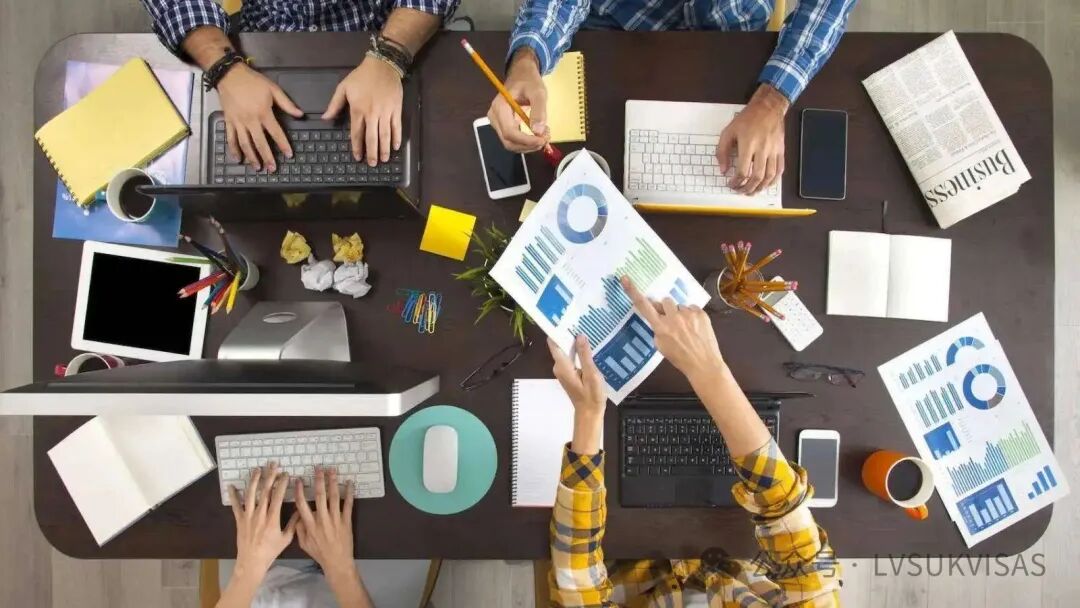 Overhead view of collaborative business team with laptops and analytics representing skilled worker visa UK 2025 professional workplace environments and sponsored employment opportunities