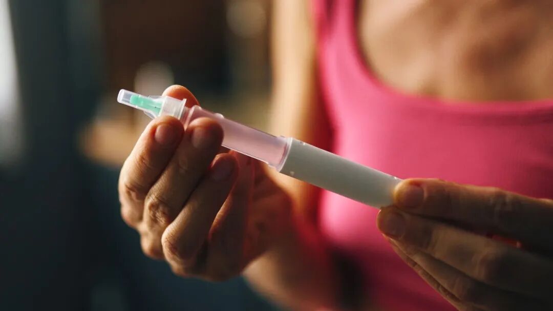 Person holding an insulin pen, preparing to inject medicine