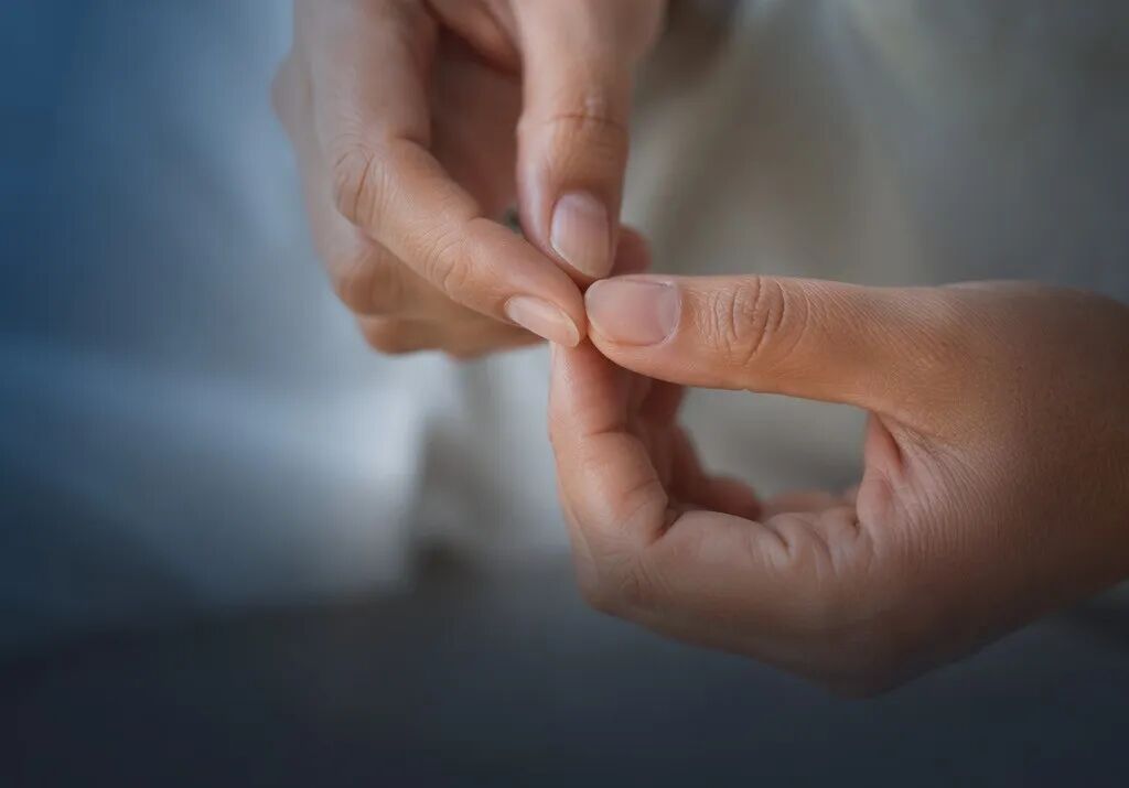 一张温暖且专业的医学摄影横版头图。画面特写了一只手正在柔和的暖光下，仔细而温柔地观察另一只手的指甲和指尖细节，呼应文中“关注肢端”的自检行为。色调以暖灰色和品牌蓝（#1996DF）为主，充满人文关怀。画面下方三分之一处为简洁的深色渐变留白，不含任何文字，方便叠加标题。