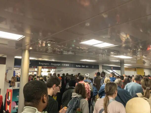 大批乘客正在穿过繁忙的机场行李托运和出口区域。