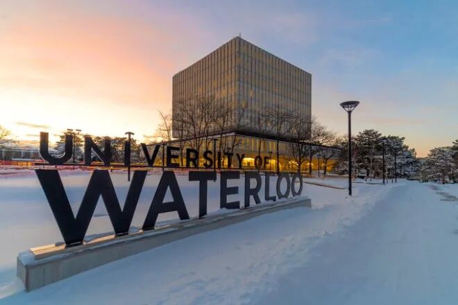 The University of Waterloo sign on main campus with the Dana Porter Library in the background on a wintery day