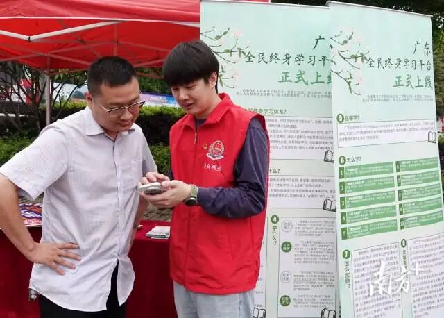 税务志愿者向群众介绍广东全民终身学习平台