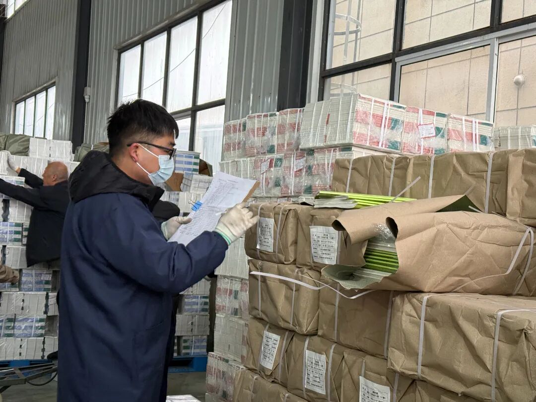 2026年3月2日固安县新华书店仓库内工作人员对照清单，逐一核对教学用书的种类与数量.jpg