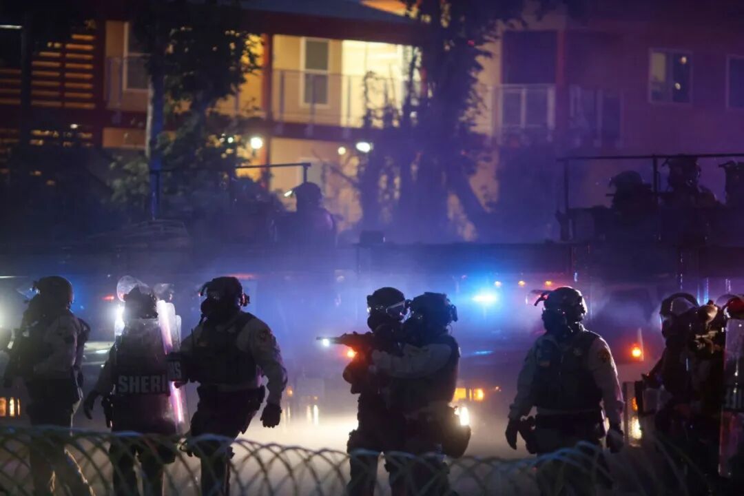 周六，执法人员在加利福尼亚州康普顿的一场抗议活动中站着。