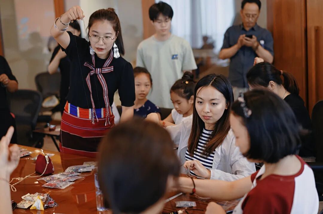 在廖静文的佤族织锦工作室里，一群来自普洱学院的学生正围着她，目不转睛地观察她手中的织锦纹样。陈龙汝男摄 2025年6月9日.jpg