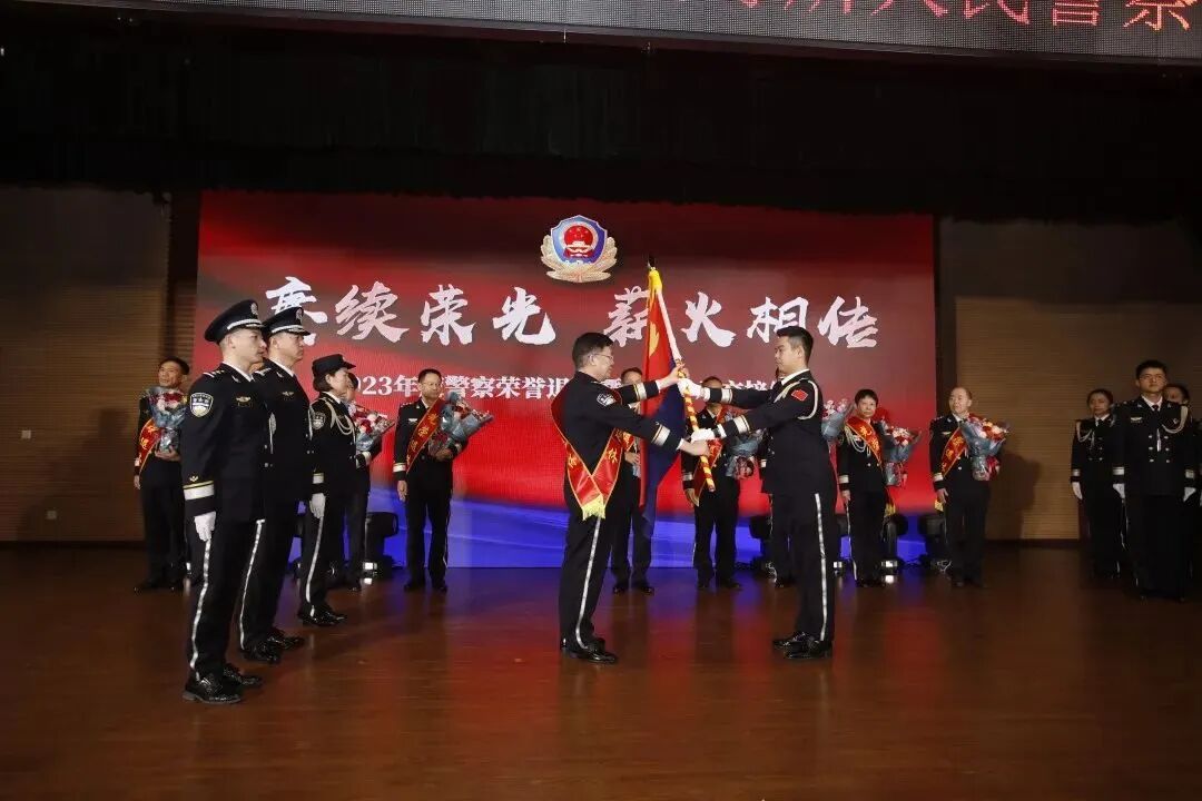 深圳一所荣休民警代表将崭新的警旗交到青年民警代表手中，也将新时代人民警察的使命任务接续传承到青年民警肩头