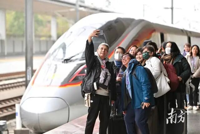 3月8日11时11分，首趟从香港西九龙站直达清远站的旅游专列驶入清远高铁站，刚下车的香港旅客与复兴号列车合影留念。 南方+记者曾亮超 摄