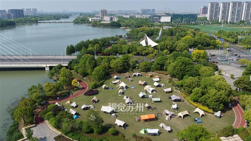 张家港沙洲湖畔大草地草木葱郁，成为市民假日休闲好去处。湖畔垂柳依依、碧波荡漾，风光如画。市民前来湖边垂钓、草坪露营、亲水游玩，亲近自然、乐享假期时光。